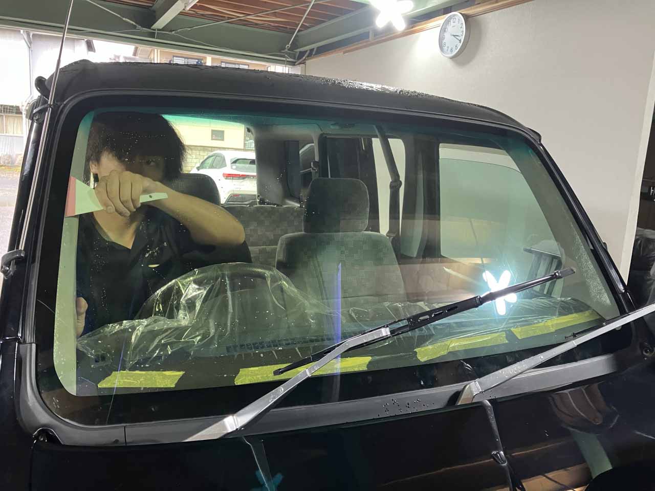 スクレイパーを使ってフィルムとガラス面の間の水分を抜いている様子